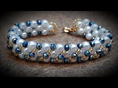 a close up of a bracelet with pearls and blue glass beads on a cloth background