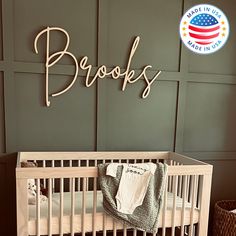 a baby crib in front of a green wall with the name brooks on it