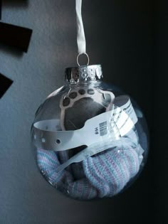 a glass ornament with a baby's foot in it hanging on a wall