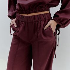 The Mirela Pants in forest burgundy are a versatile and comfortable addition to your wardrobe. These high-waisted pants feature wide legs for a relaxed and stylish look. They come with side pockets for added convenience and centre seam for a tailored fit. These pants feature an elastic waist that adjusts to sizes XS to L, ensuring a perfect fit for your body. Crafted from 100% soft and breathable Tencel. Consciously produced in our own atelier in Romania in limited quantities. 100% Tencel. Wash at 30 degrees, medium heat ironing. Our recommendation for washing clothes is to use either a mild detergent or one specifically designed for wool and silk fabrics. Conventional "color detergents" often contain enzymes that can break down the fibers or fade the colors. While they may work well with Knit Loungewear, Corporate Chic, Silk Fabrics, Stocking Fillers For Her, Holiday Party Outfit, Wide Legs, Independent Designers Fashion, Straight Pants, Badger