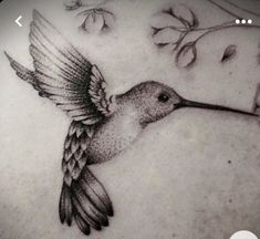 a hummingbird tattoo on the back of a woman's stomach