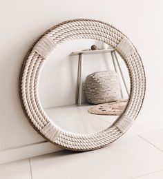 a round mirror sitting on top of a white floor next to a shelf with a basket