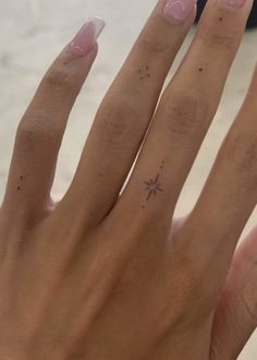 a woman's hand with a small star tattoo on her left thumb and finger