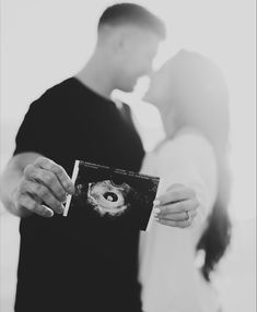 a man and woman holding an album in front of each other with their faces close together