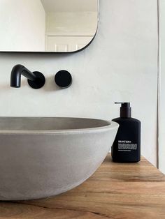 a bathroom sink sitting next to a mirror and soap dispenser on top of a wooden counter