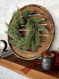 a wreath on top of a wooden shelf next to a candle and some other items