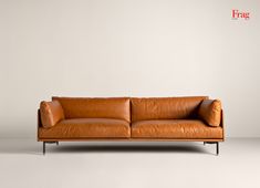 a brown leather couch sitting on top of a white floor next to a gray wall