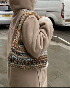 a woman is standing on the sidewalk with her purse