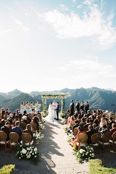 an outdoor wedding ceremony at the top of a mountain with mountains in the back ground