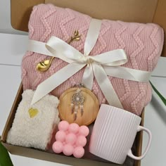 a pink blanket and some other items are in a box with a white ribbon around it