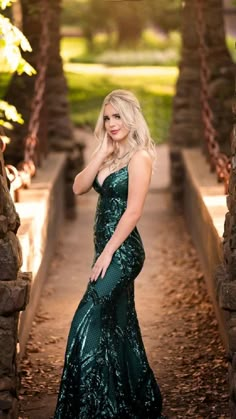 a woman in a long green dress posing for a photo with her hand on her hip