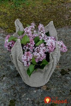 a bunch of flowers that are sitting in a bag on the ground with grass behind it