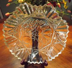 a glass plate with a tree on it sitting on a table next to some flowers