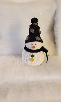 a snowman wearing a black hat and scarf sitting on top of a white chair