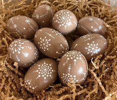 six chocolate eggs with white designs in a nest