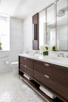 a bathroom with two sinks, a toilet and a large mirror on the wall above it