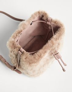 Fleecy shearling bucket bag The classic bucket style is presented in a very soft, precious version in this new Fleecy shearling bucket bag. The refined material’s plush, full effect enhances the accessory’s relaxed lines with a sophisticated touch. The leather handles and drawstring introduce a texture contrast and represent functional details that are perfect for a little girl’s daily adventures. Fur Clutch Bag, Fuzzy Bag, Winter Purses, Texture Contrast, Winter Handbags, Fur Clutch, Fur Bag, Felt Bag, Boutique Online