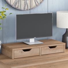 a flat screen tv sitting on top of a wooden table next to a lamp and vase