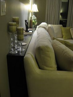 a living room filled with white couches next to a tall table topped with wine glasses