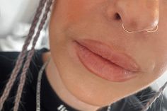 a close up of a woman with braids on her nose and nose ring in front of her face