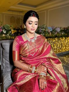 a woman sitting in a chair wearing a pink and gold sari