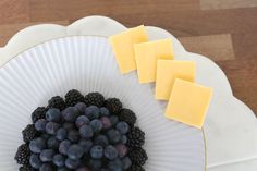 grapes and cheese are arranged on a paper plate