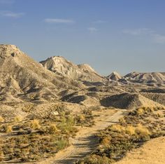 a dirt road in the desert with mountains in the background