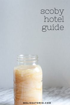 a glass jar filled with liquid sitting on top of a white marble counter next to a wall