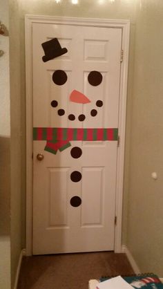 a door decorated with a snowman's hat and scarf on it, next to a christmas light