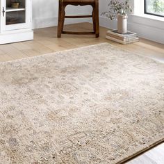 an area rug in the corner of a room with a chair, table and window