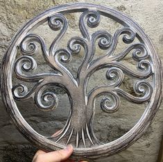 a person holding up a metal plate with a tree on it