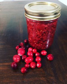 cranberry sauce in a glass jar next to it's contents on a wooden table