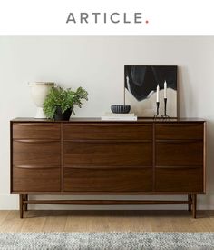 a wooden dresser sitting on top of a hard wood floor next to a white wall