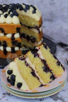 a cake with blueberries and white frosting is on a plate next to another cake