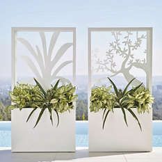 two white vases with plants in them sitting on a table next to a pool