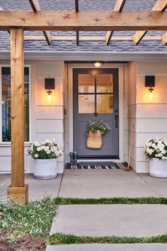 two planters with flowers are on the front porch