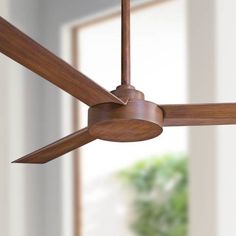 a ceiling fan with wooden blades in a room