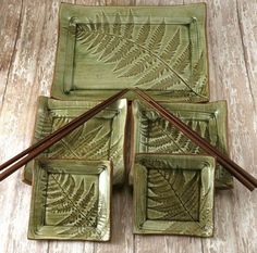 four green plates with chopsticks in them on a wooden table next to two bowls