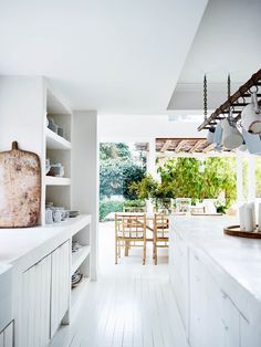 an open kitchen with white cabinets and wood flooring on the walls, along with wooden dining table and chairs