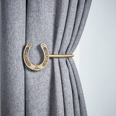 a curtain with a gold horseshoe handle on it's side hanging from the top of a drapes