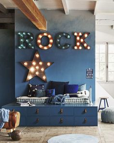 a living room with blue walls and lights on the wall, including a bench in front of it