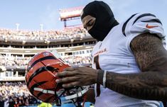 a football player wearing a black mask and holding a helmet in front of an empty stadium