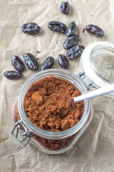 a jar filled with cocoa beans next to a spoon