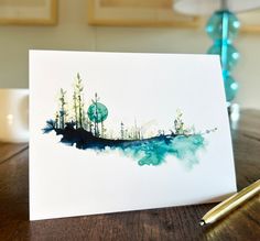 a card with watercolor painting on it sitting on a table