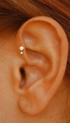 a woman's ear is shown with two small diamond studs on the side