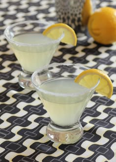 two glasses filled with lemonade sitting on top of a table