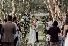 a bride and groom standing under an arch with flowers on it at the end of their wedding ceremony