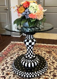 a black and white vase sitting on top of a glass table with flowers in it