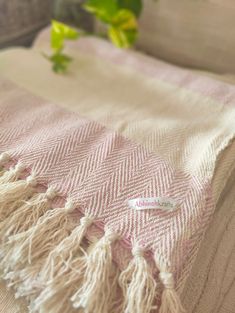 a pink and white blanket sitting on top of a bed next to a green plant