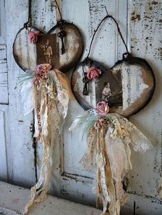 two heart shaped wall hangings with flowers and ribbons on them, attached to an old door